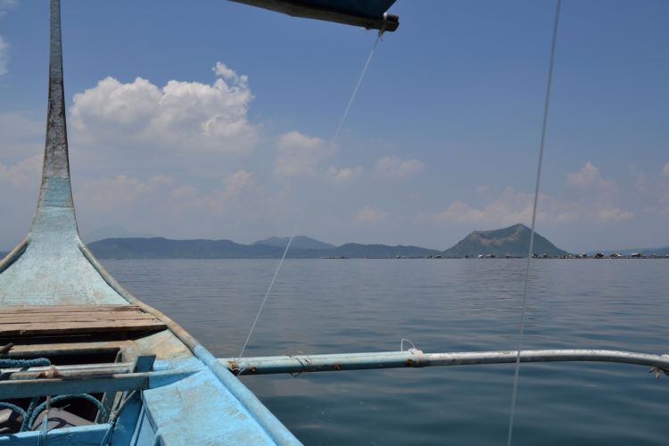 Filipino boat with Mount Taal Volcano island in the distance