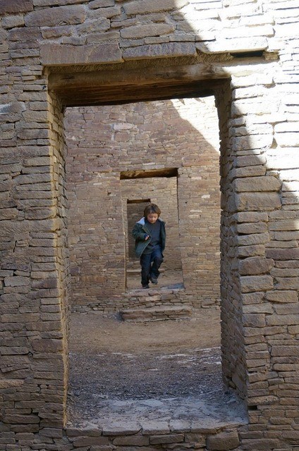 A boy running the doorways in the ruins of Chaco Canyon.