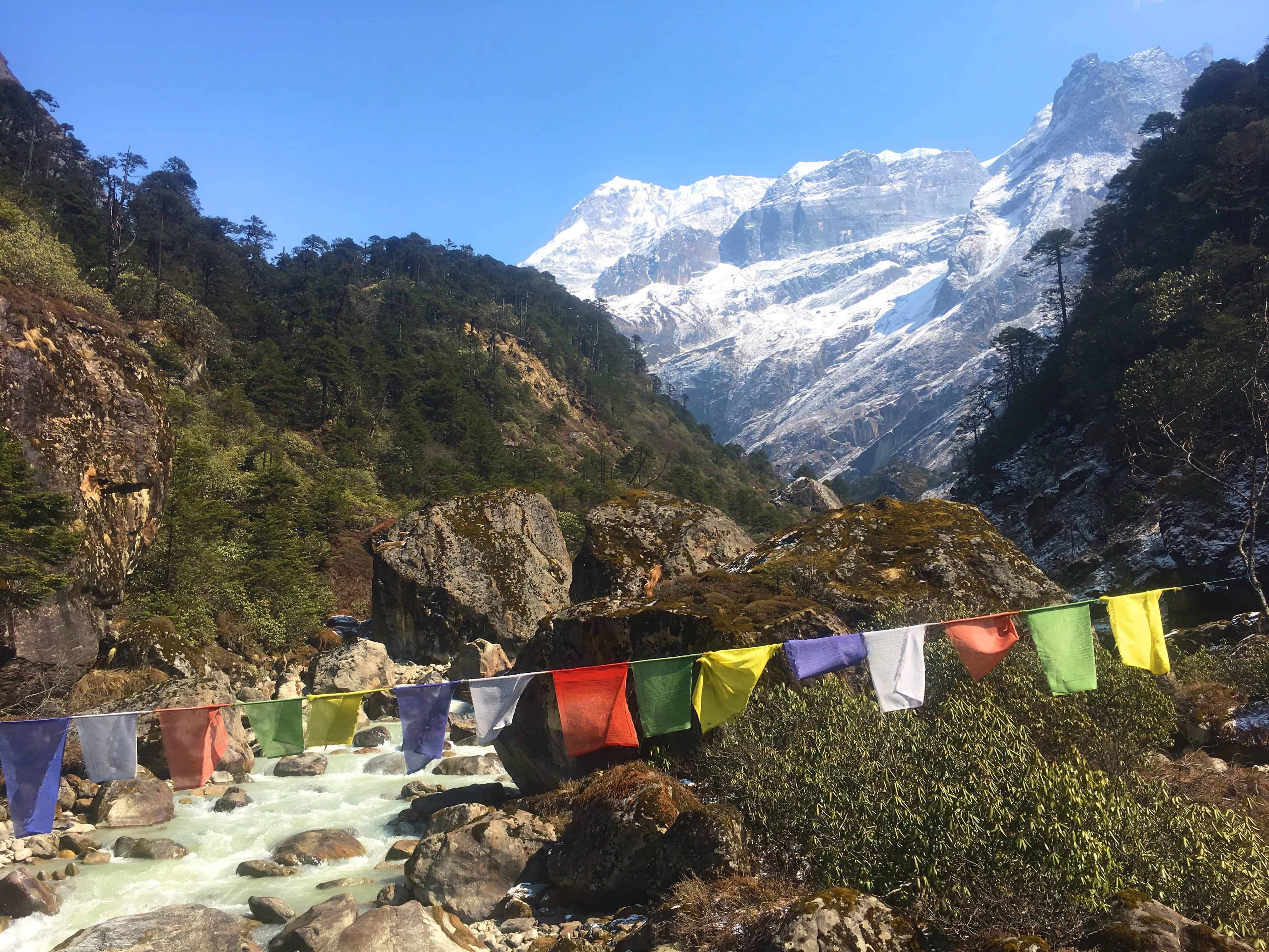 Prayer flags flutter over a stream in Nepal