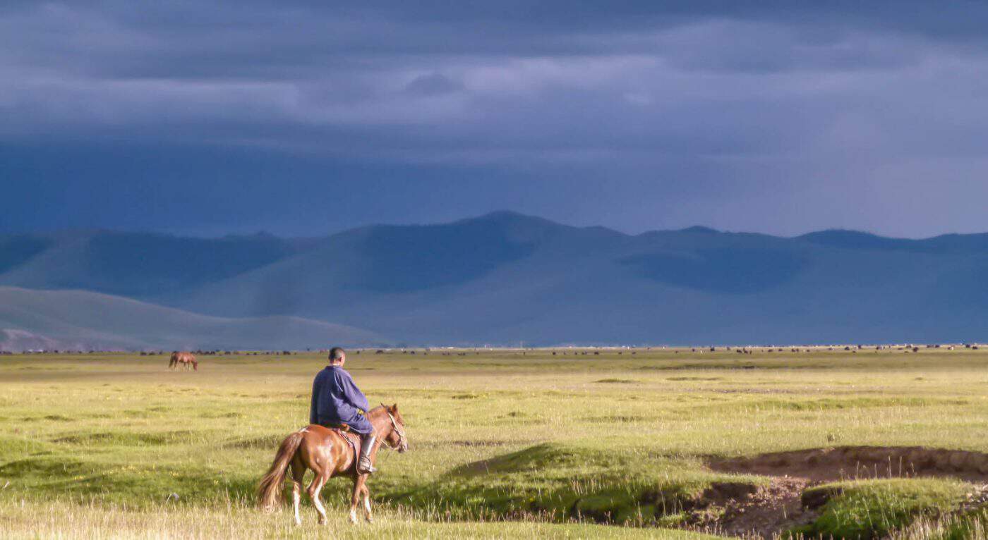 A local on the Mongolian steppe trots away on horseback after leaving us with a gift of dried cheese