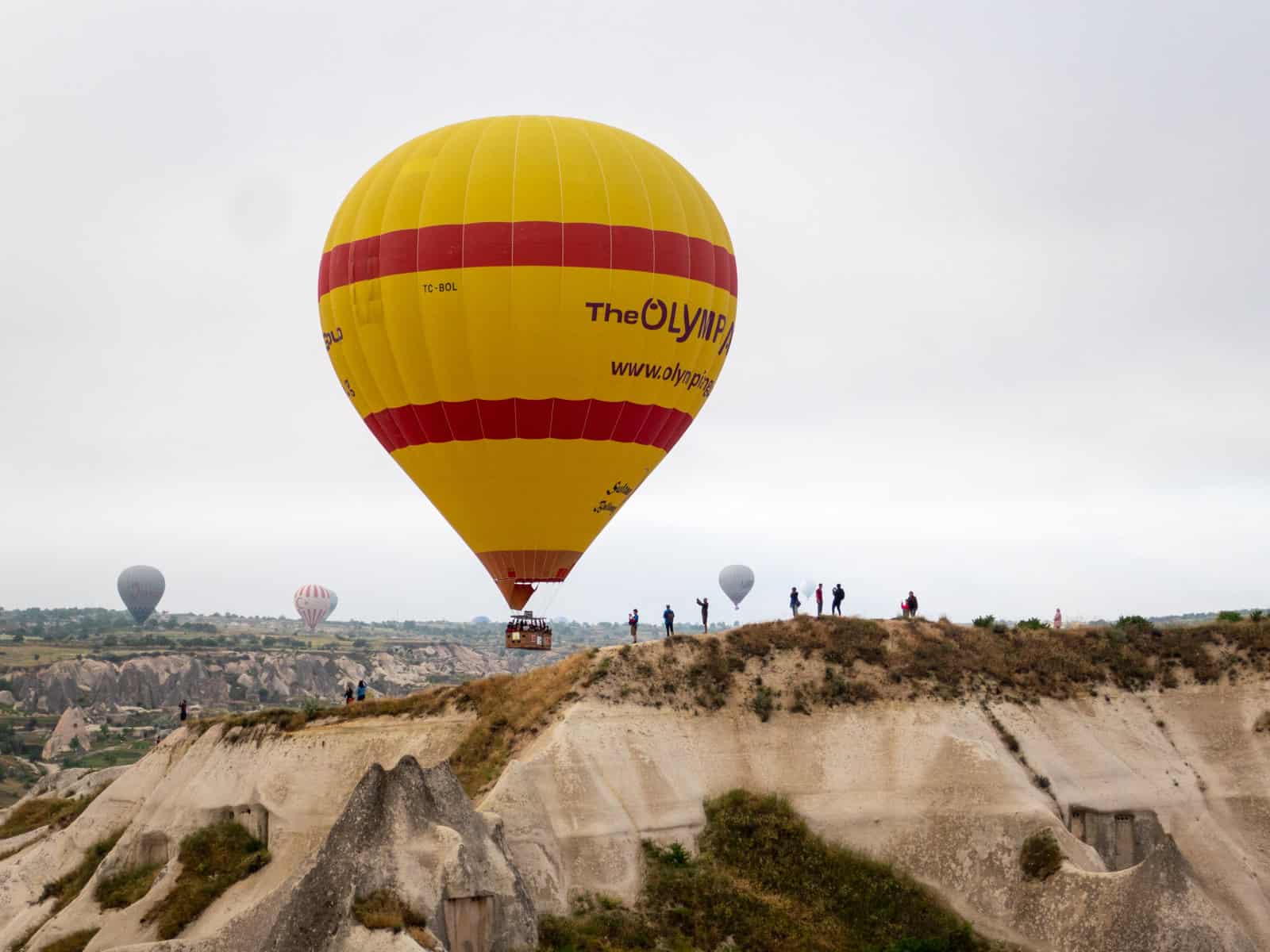 A hot air balloon passes a scenic outlook