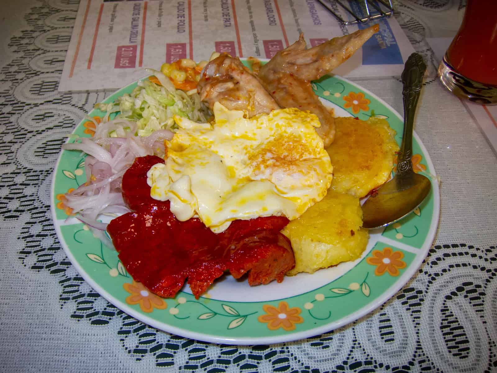 Llapingachos served with chicken, chorizo, a fried egg, and salad is typical of Ecuadorian food.