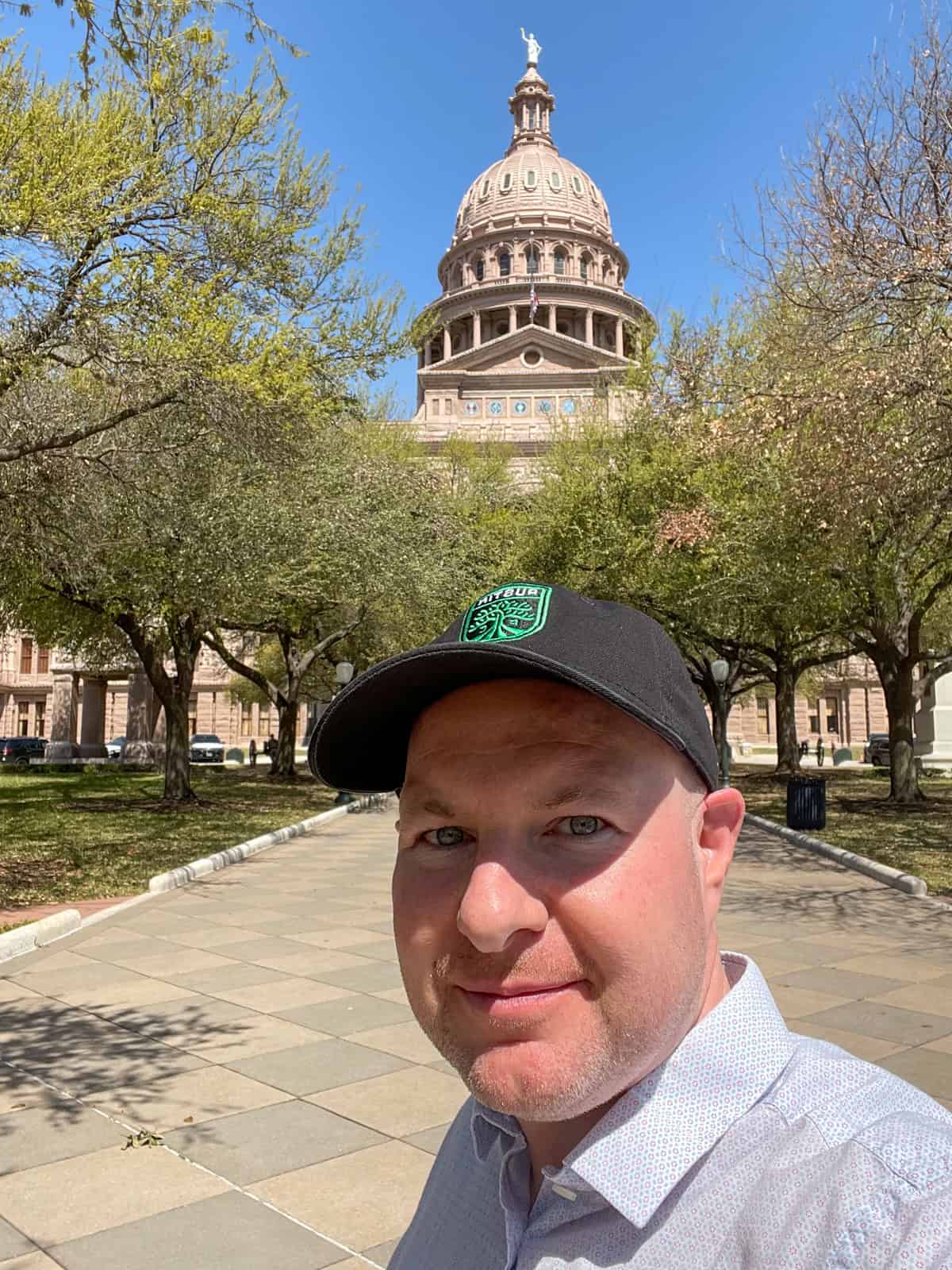 Dave outside the Texas State Capitol, wearing a new Austin FC hat.