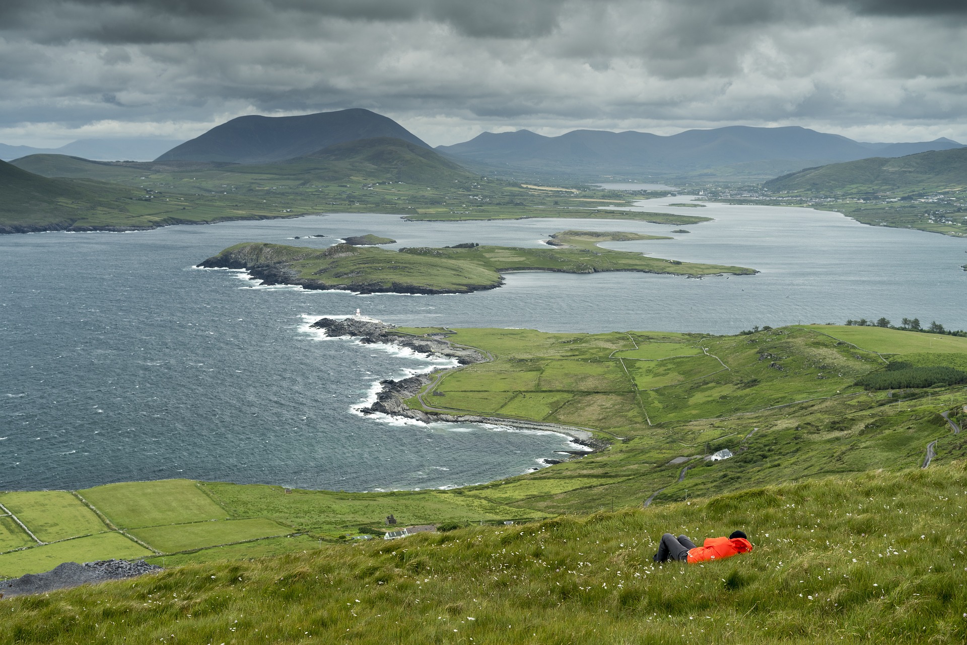 Seorang pejalan kaki berbaring di rerumputan dengan pemandangan indah di Irlandia