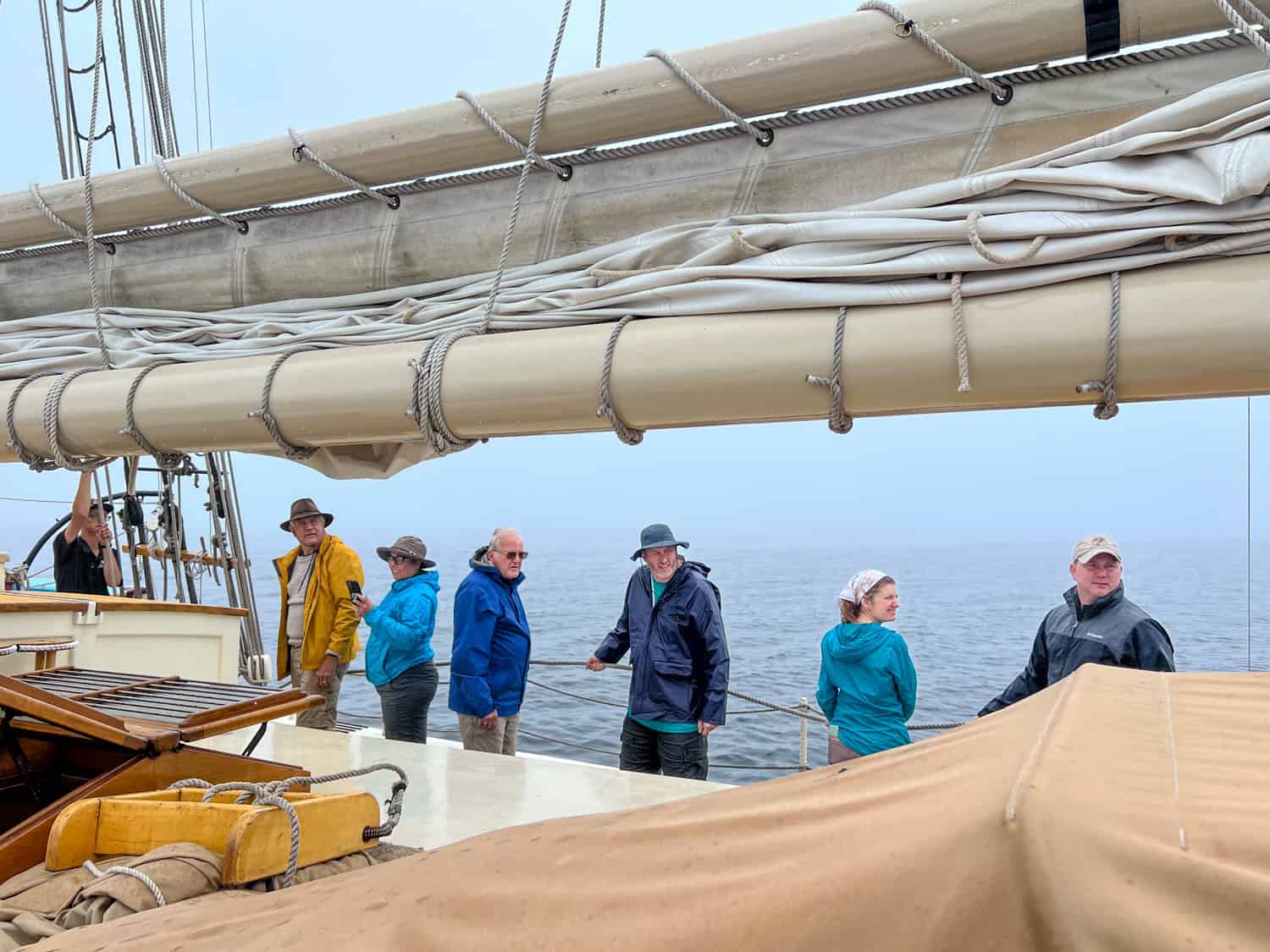 Guests and crew prepare to raise the mainsail during a Maine windjammer cruise aboard the J & E Riggin.