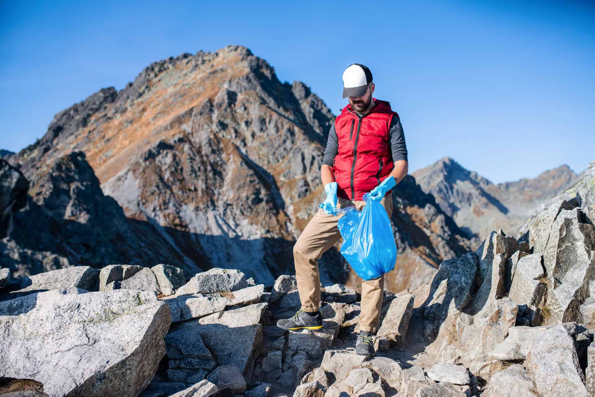 A man collecting trash in the mountains (photo by Getty Images, Unsplash+ license)