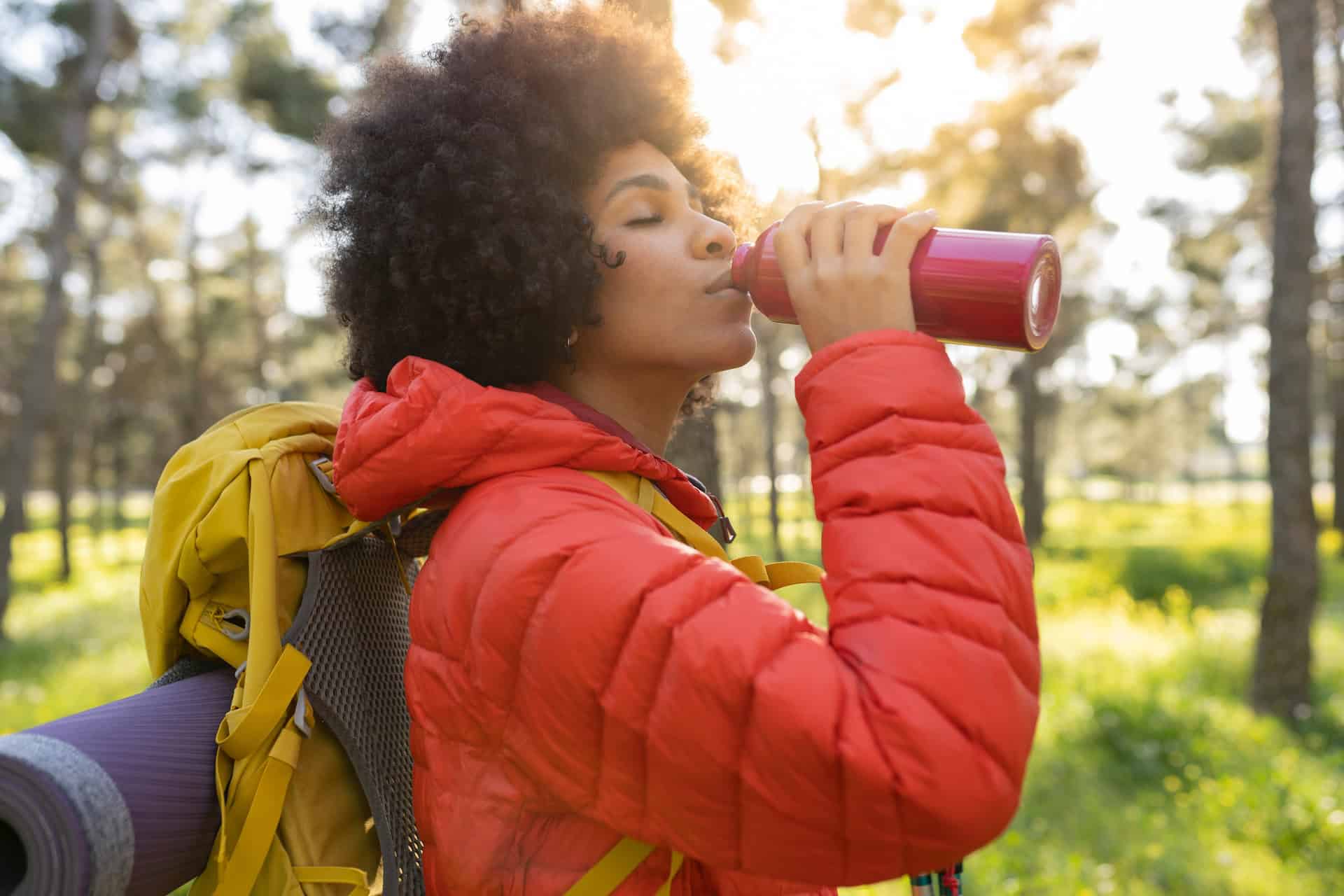 A hiker drinking from a reusable water bottle, a popular sustainable travel practice. (photo: Getty Images)