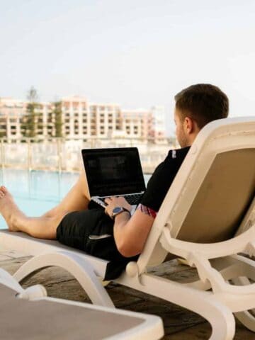 A man on a laptop by the pool.