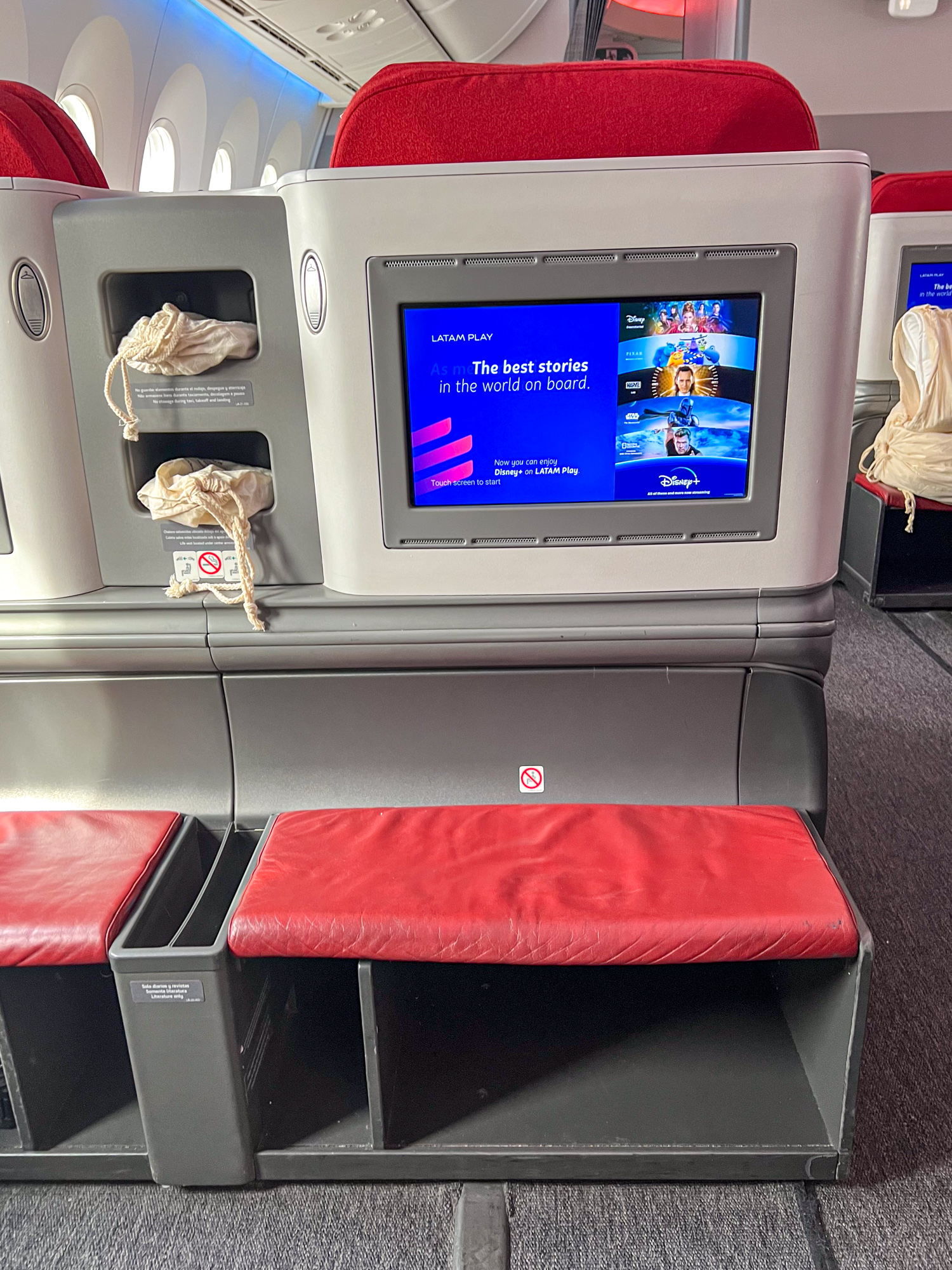 In-flight entertainment screen, foot rest, and storage space.