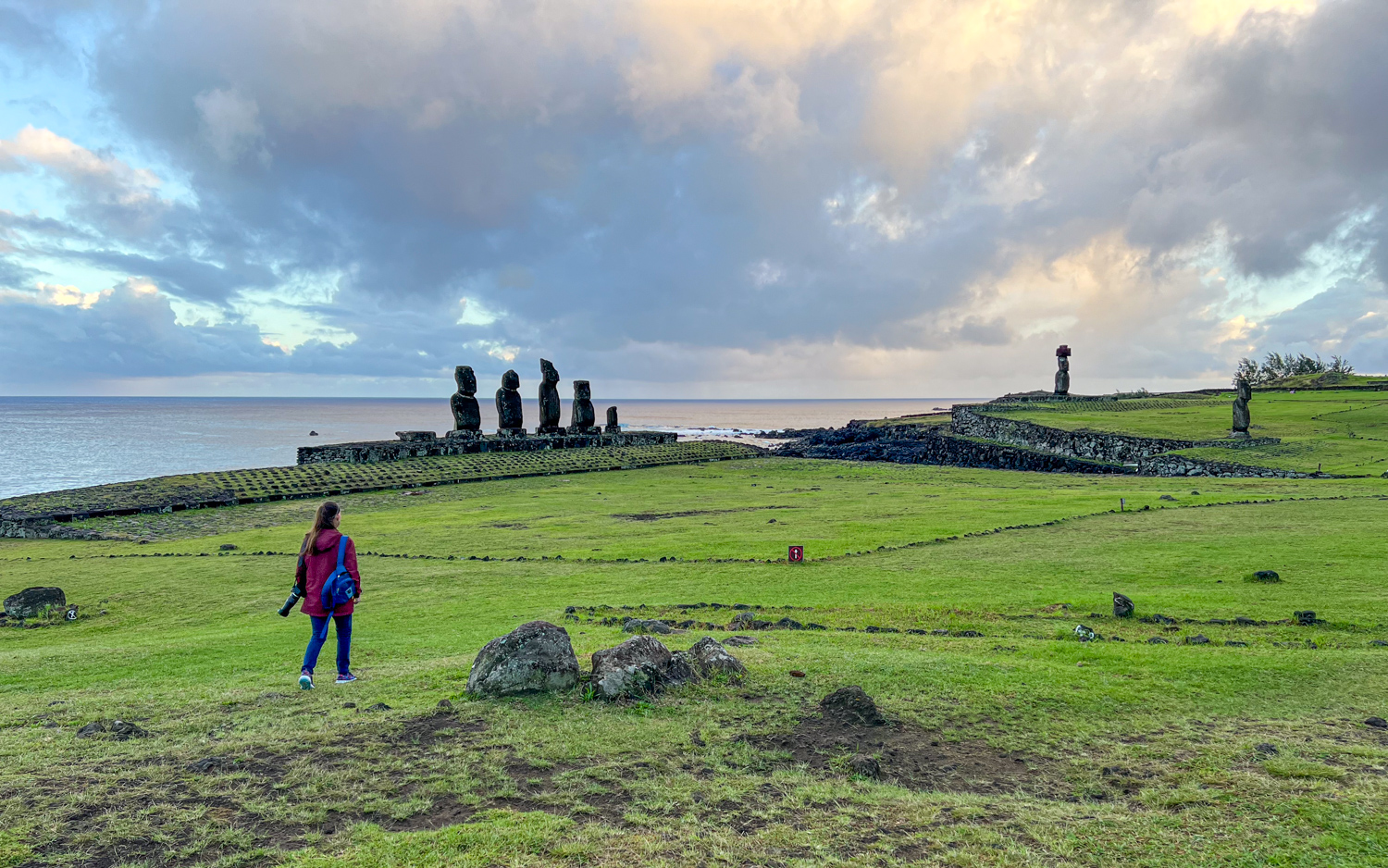 Kel walks toward the moai statues at sunrise.