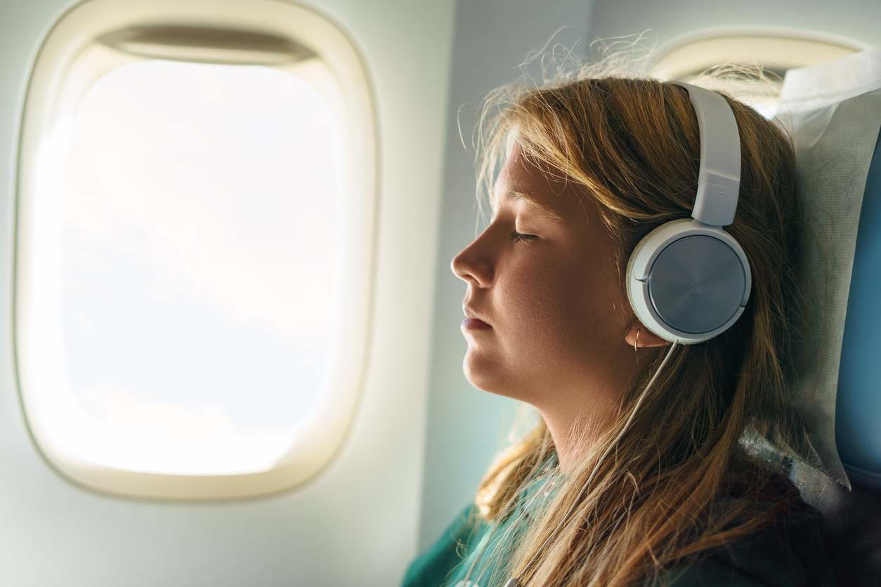 Woman with headphones listening to a travel audiobook on a flight  (photo: Eugen Fedorov).