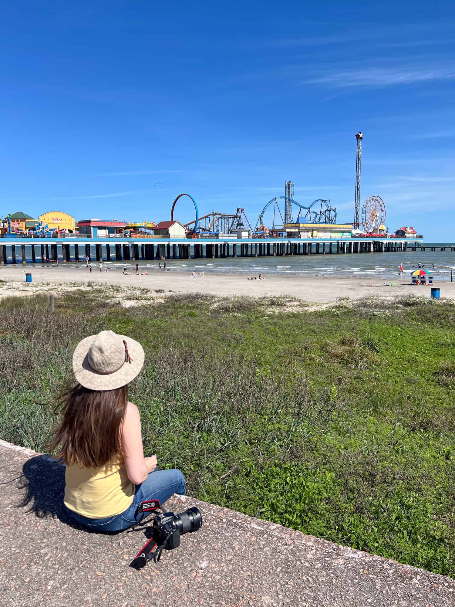 Sitting on the Seawall, Kel looks out at the Galveston Island Historic Pleasure Pier.