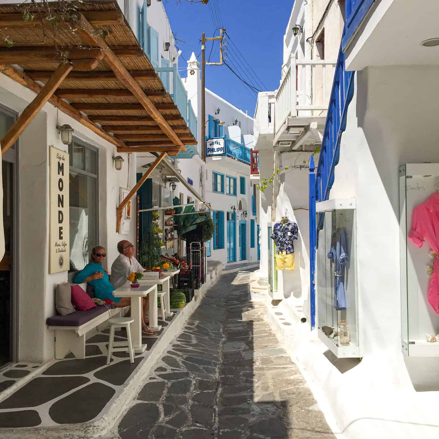 A cafe, shops, and a hotel line a pedestrian alley in Old Town Mykonos.