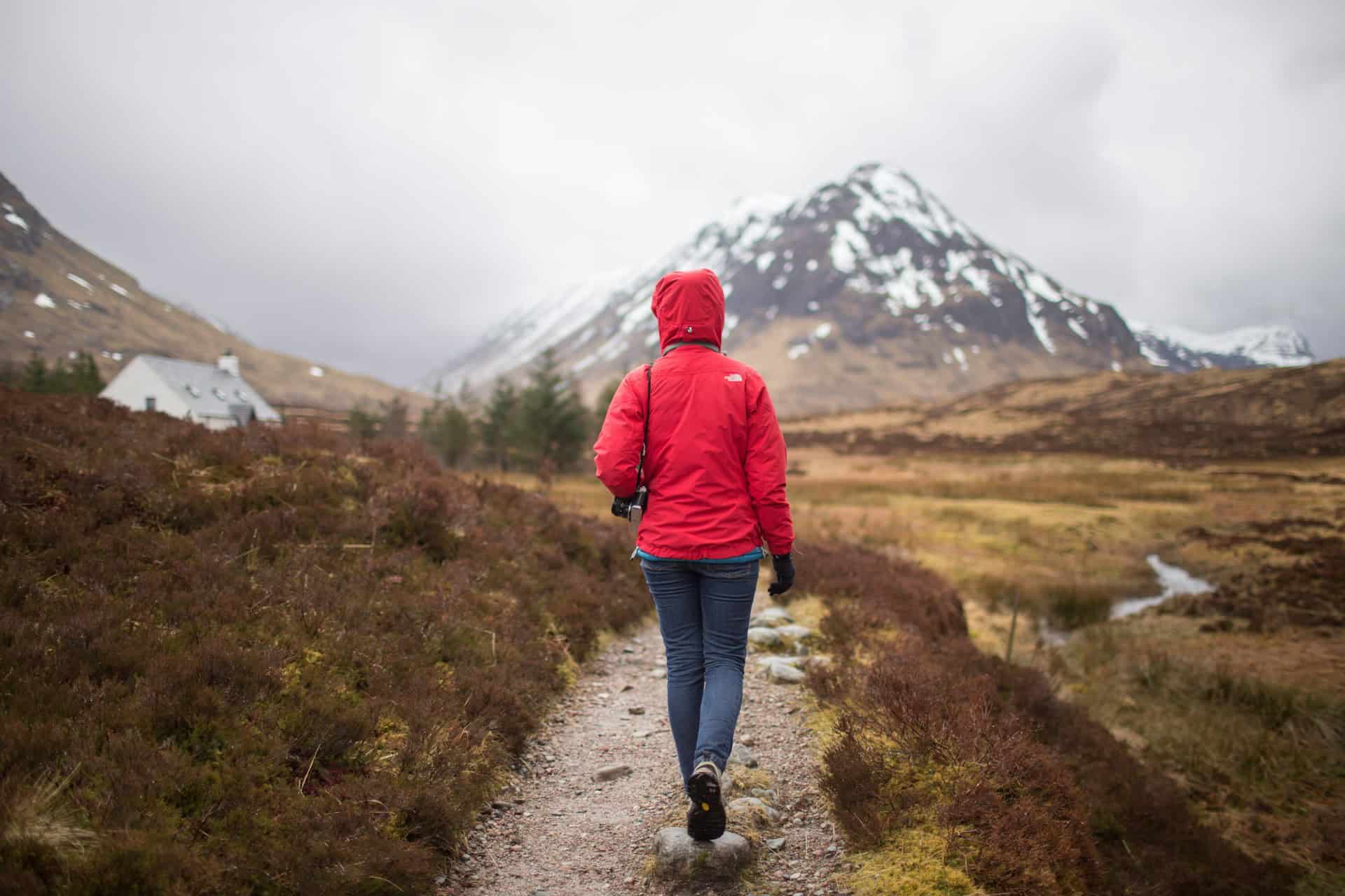 A hiker in a red jacket in Glencoe, Scotland (photo: Danka & Peter, Unsplash).