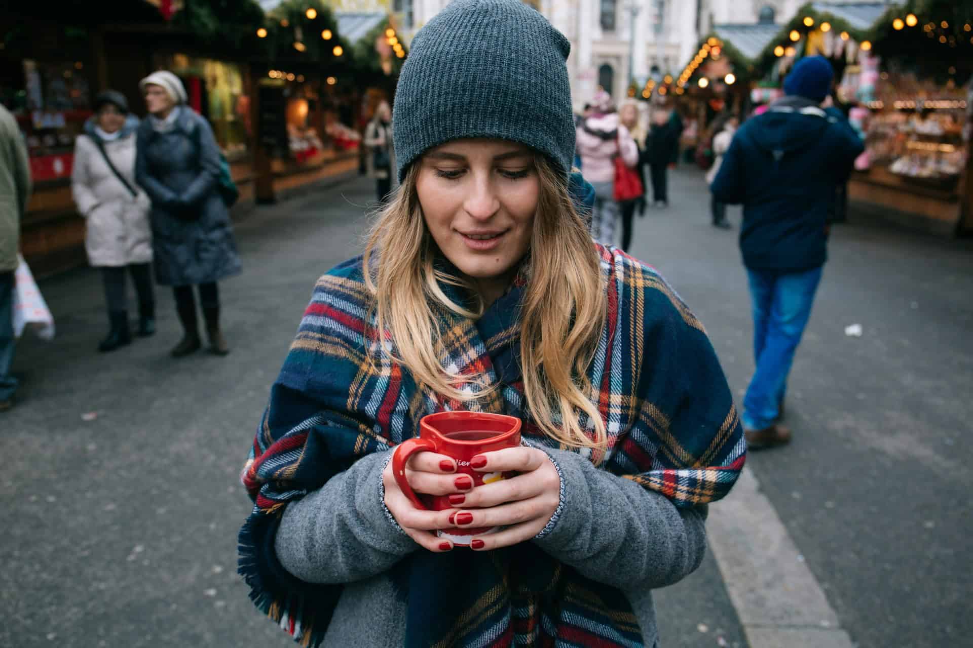 Woman with wine at a Christmas market in Vienna, Austria (photo: Alisa Anton, Unsplash).