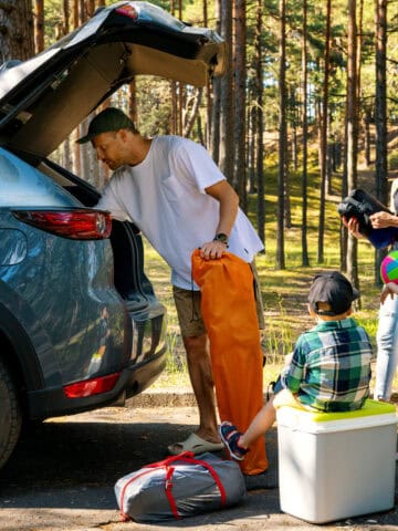 Family unpacking camping gear on a road trip (photo: ronstik, iStock).