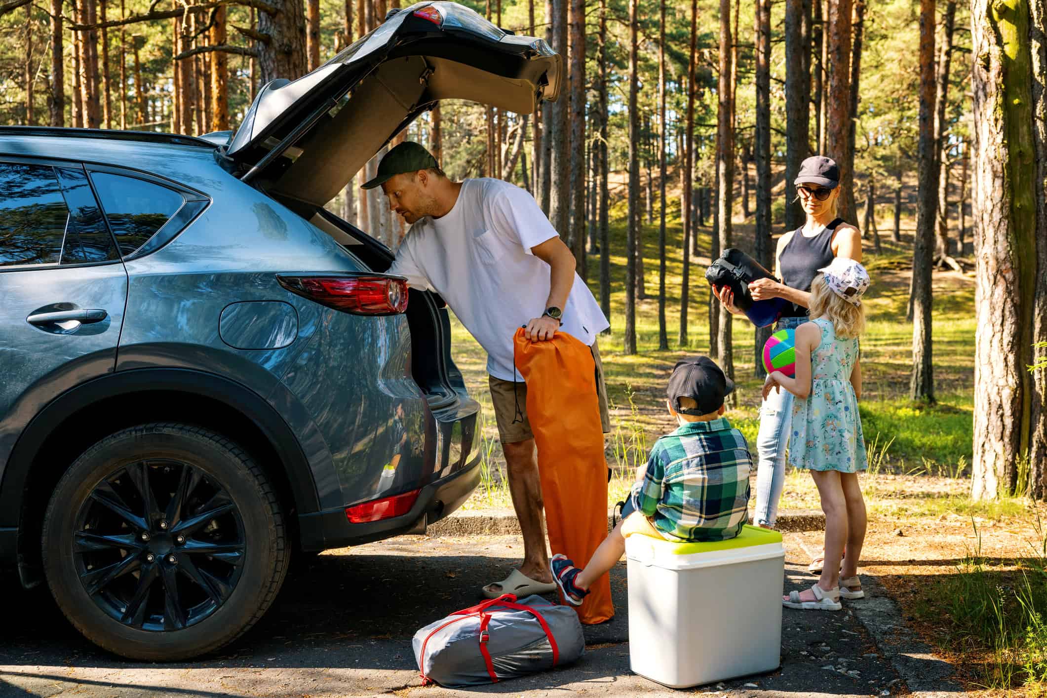 Family unpacking camping gear on a road trip (photo: ronstik, iStock).