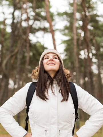 A woman smiling while hiking in the forest (photo: Freepik).