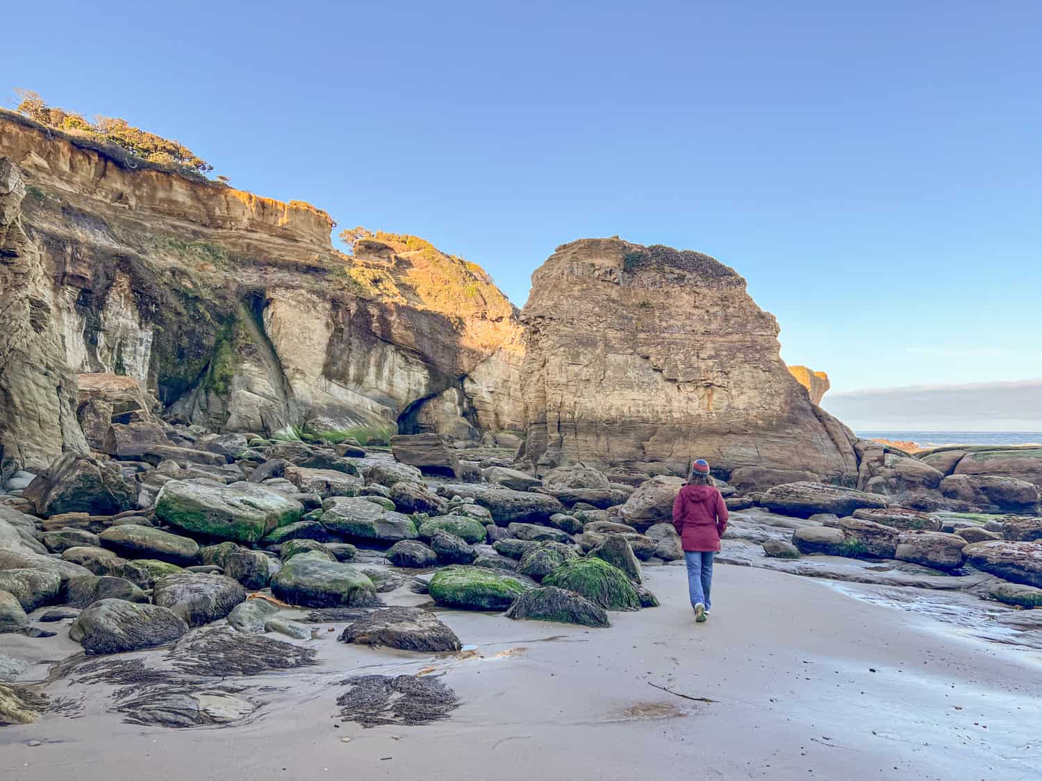 Kel walks across Otter Crest Beach on the way to Devils Punchbowl.