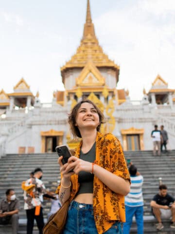 A woman using a smartphone at Wat Traimit in Bangkok (photo: Oleh Slobodeniuk, iStock).