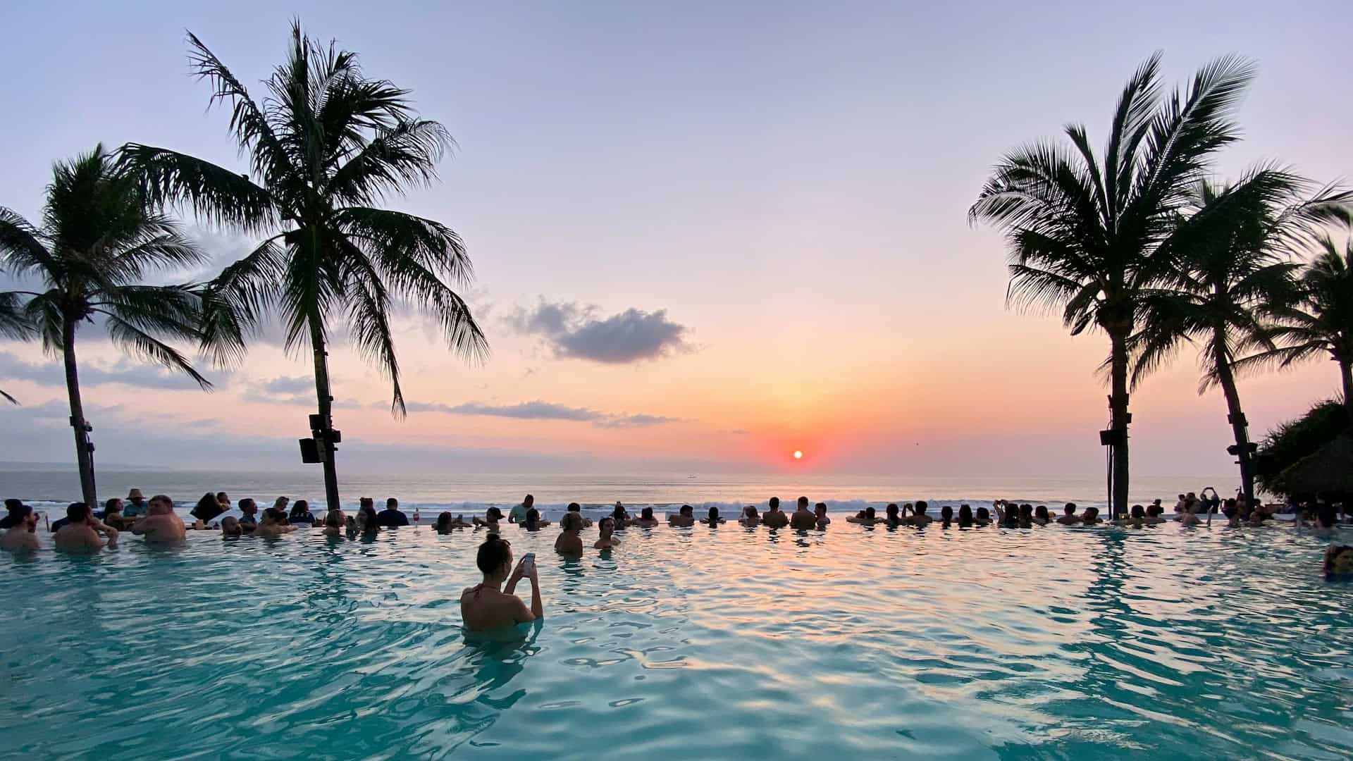 Travelers watch sunset from an infinity pool at Seminyak Beach in Bali (photo: Ern Gan, Unsplash).