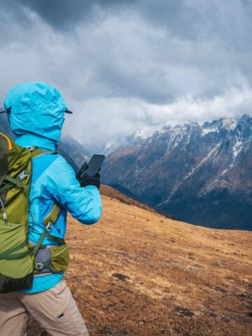 Backpacker uses iPhone trekking mountains Asia (photo: lzf, iStock).