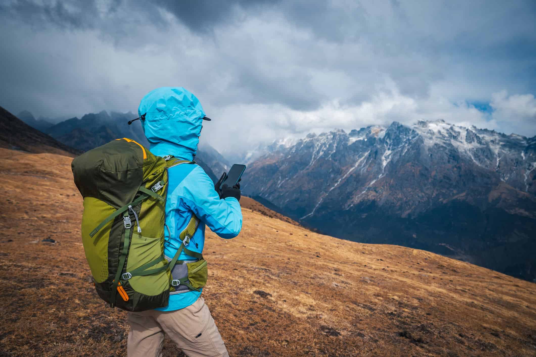 Backpacker uses iPhone trekking mountains Asia (photo: lzf, iStock).