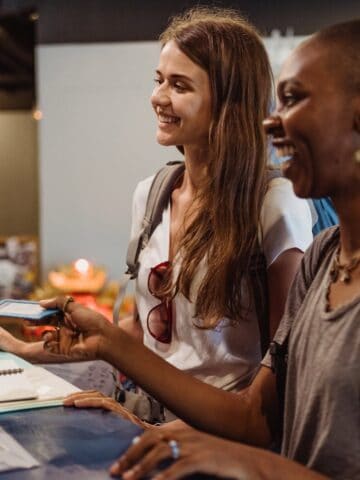 Two young women check-in at a hostel (photo: Ketut Subiyanto, Pexels).