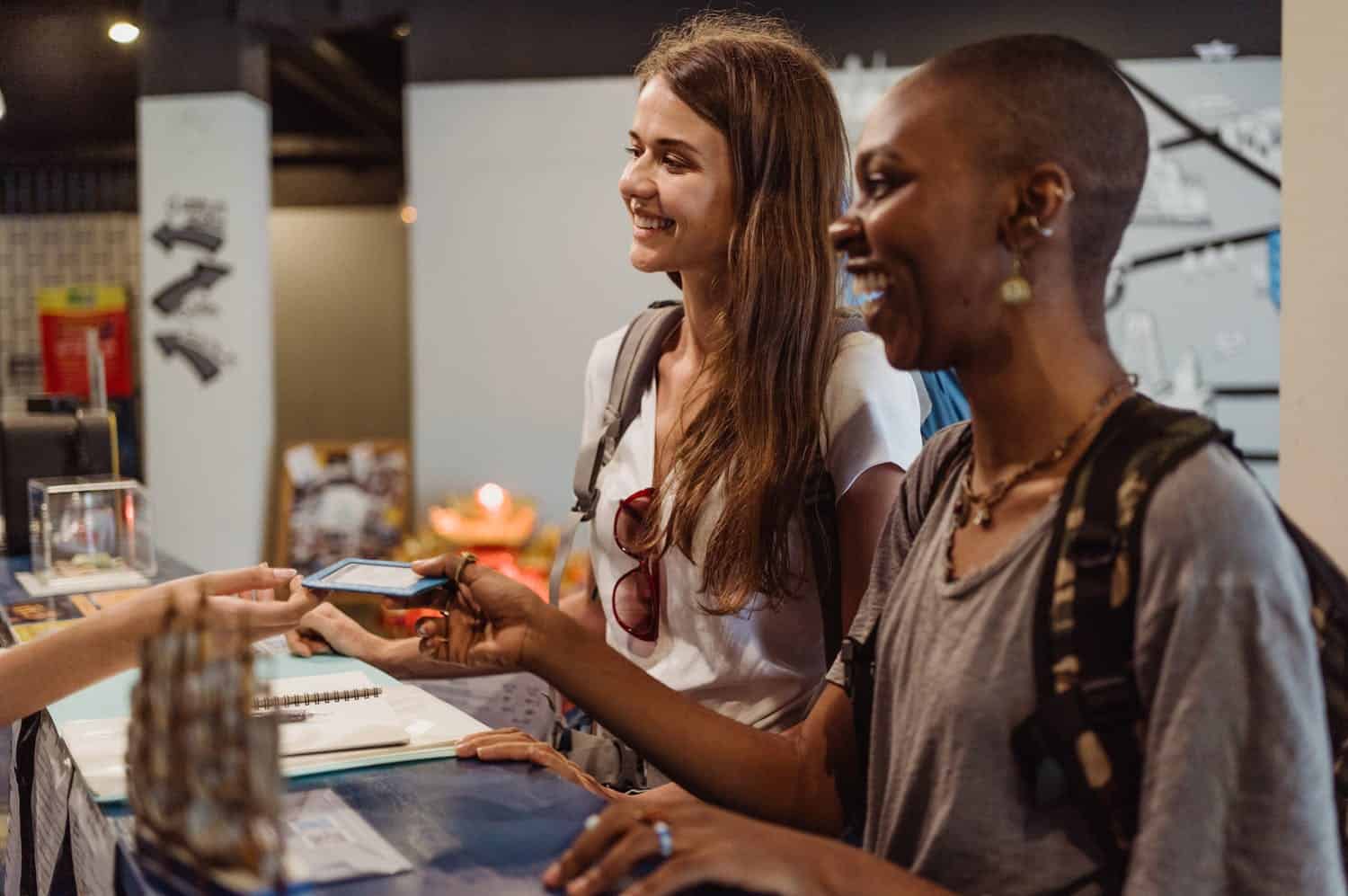 Two young travelers checking-in with cashless pay at a hostel (photo: Ketut Subiyanto).