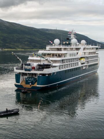Swan Hellenic SH Vega expedition cruise ship sailing in Arctic waters near mountainous coastline