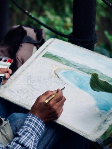 Traveler painting a watercolor landscape outdoors during a trip to Japan