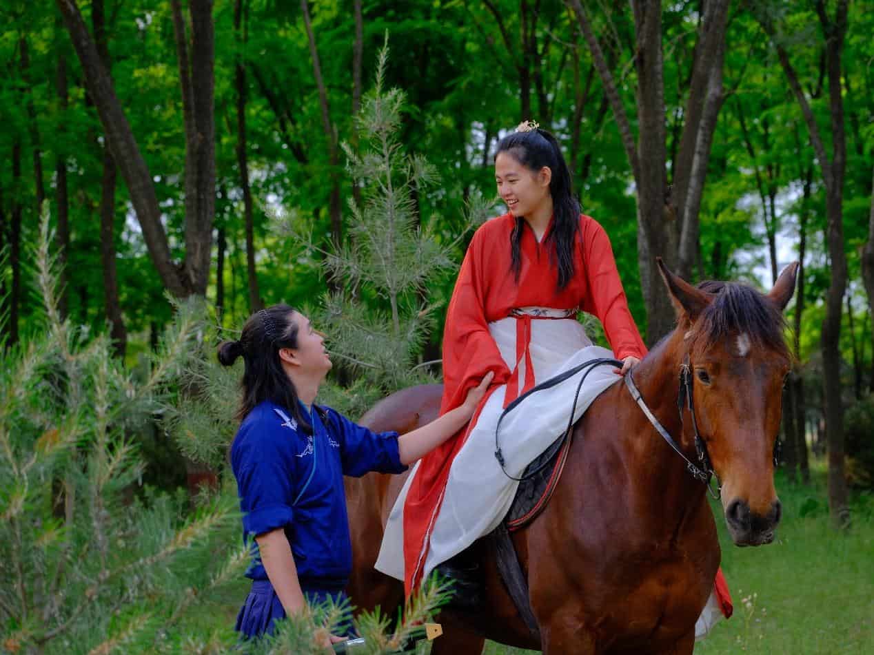Travelers in traditional Chinese clothing during a horseback riding experience near Beijing