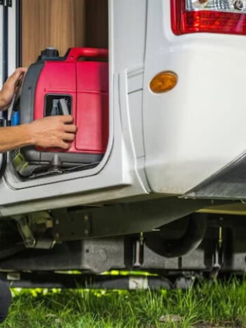 Traveler preparing a portable generator beside an RV while dry camping.