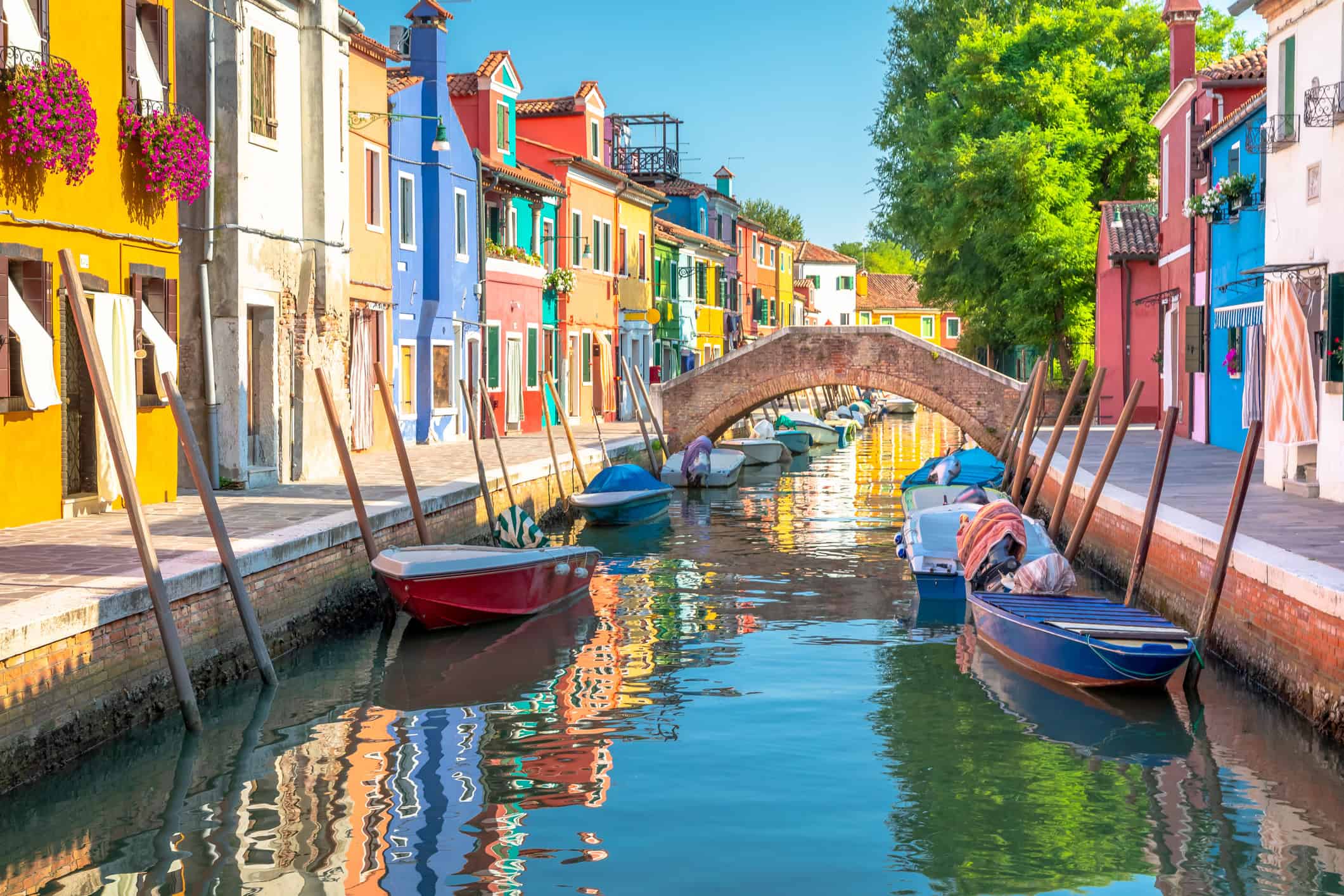 Colorful houses and small boats along a canal in Burano, Italy