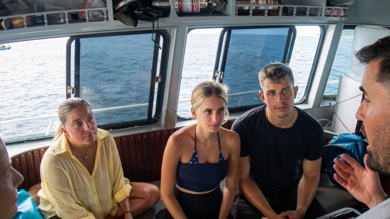 Three divers listening to an instructor aboard a boat in Thailand.