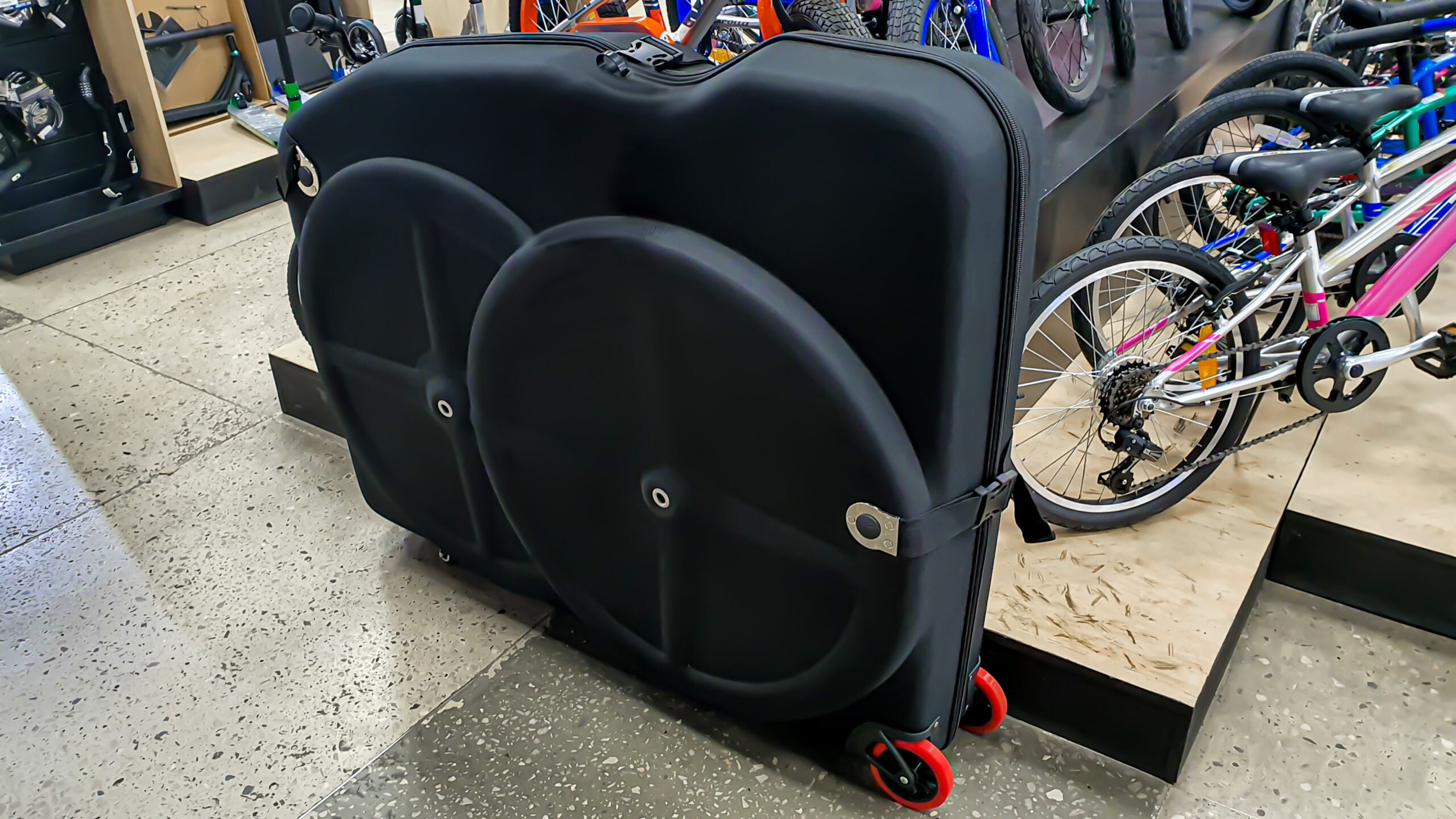 Hard-sided bicycle travel case with wheels in a bike shop