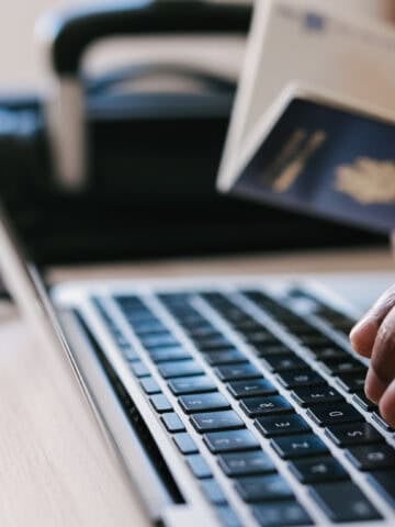 Traveler booking a hotel online with a laptop, passport and payment card