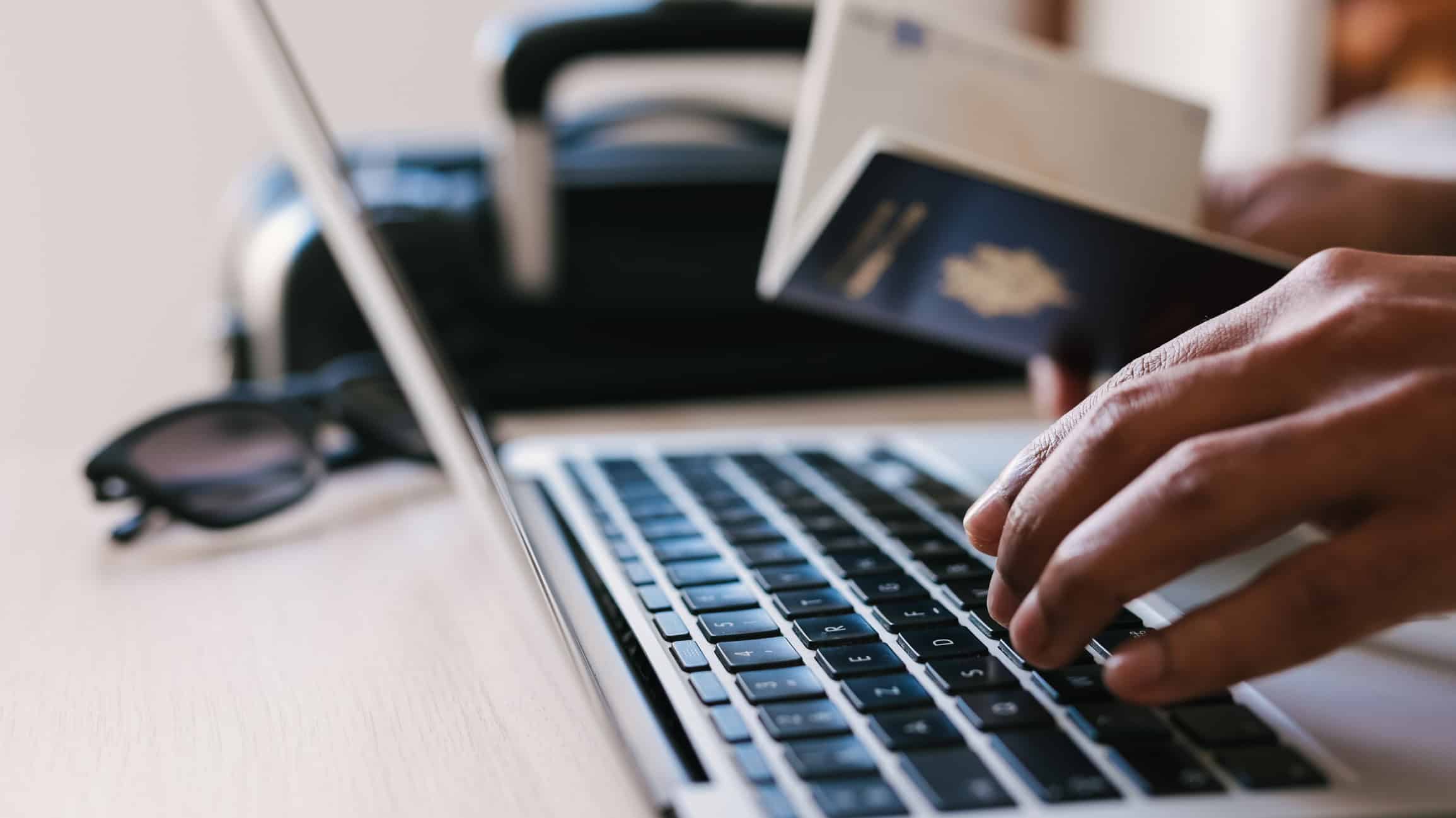 Traveler booking a hotel online with a laptop, passport and payment card