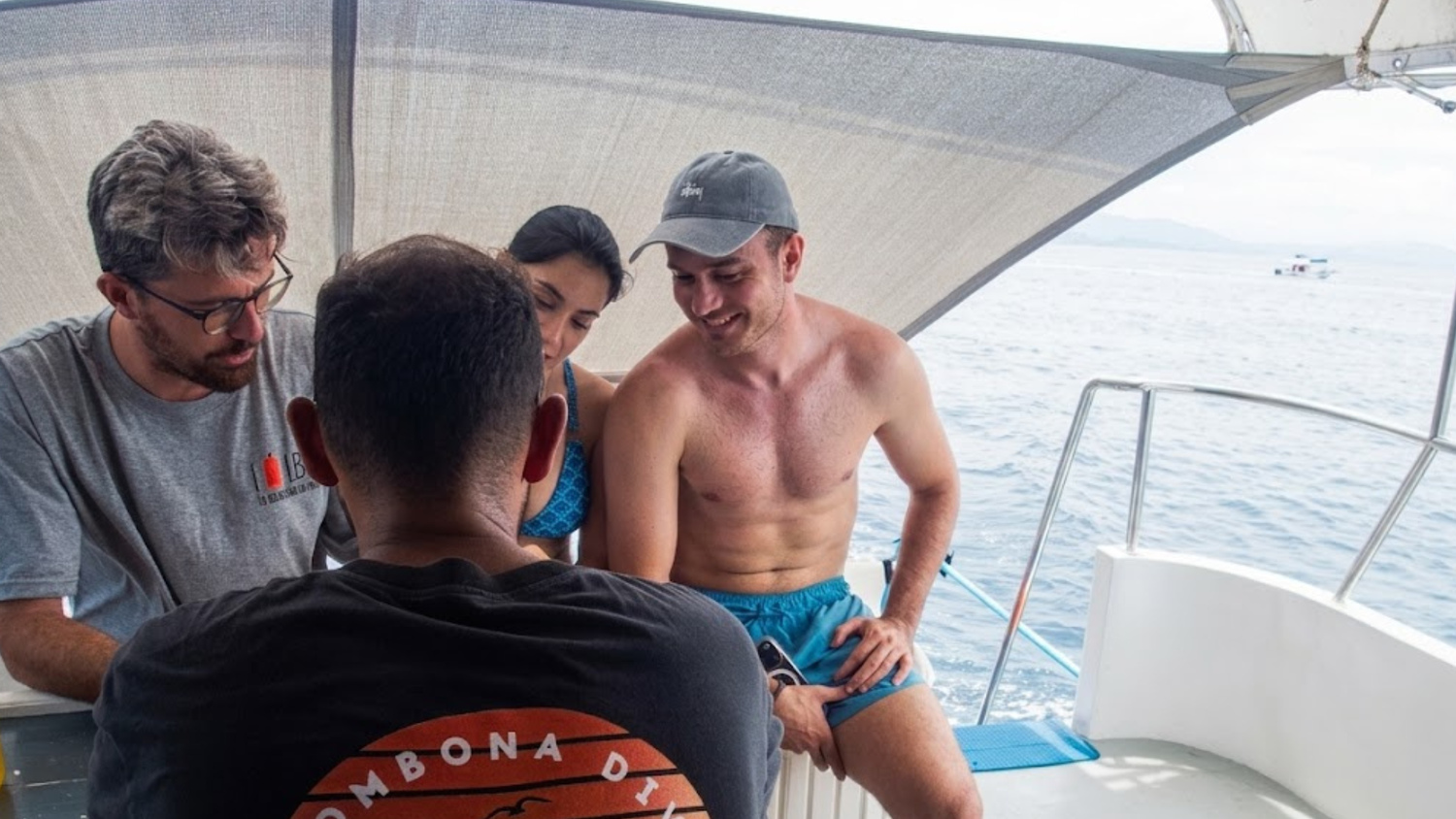 An LB Diving instructor briefs three divers aboard a dive boat in Koh Tao.
