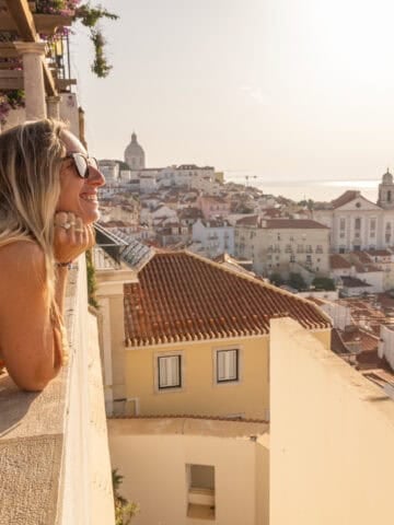 Woman overlooking Lisbon's Alfama district and the Tagus River in Portugal.