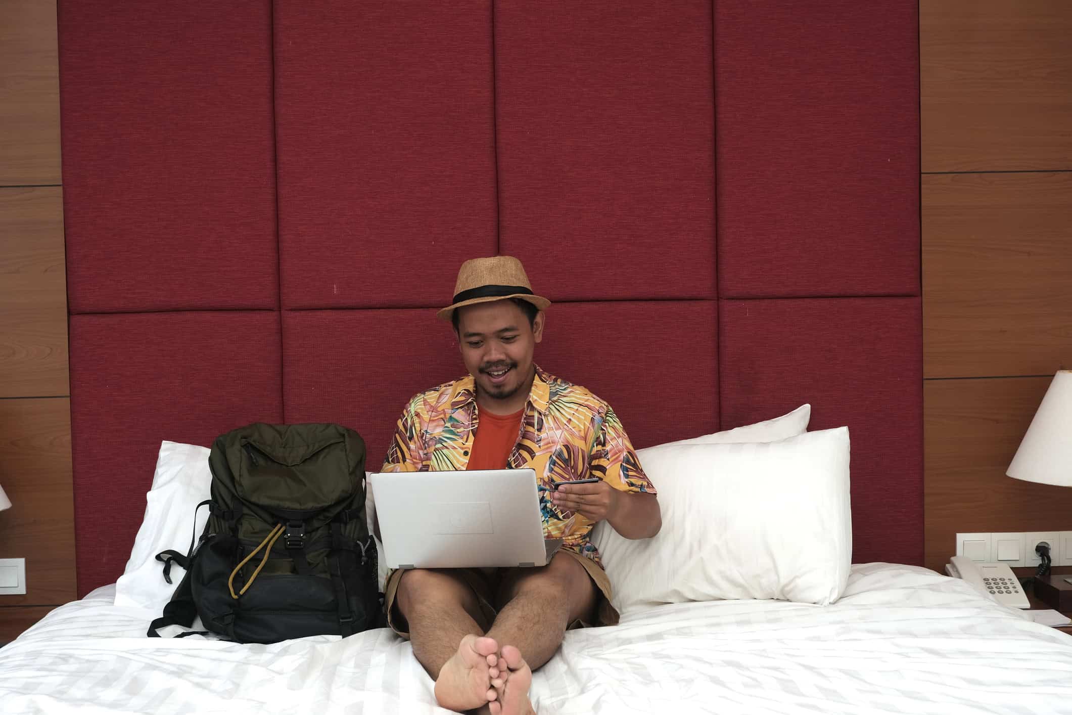 Traveler with a backpack using a laptop in a hotel room
