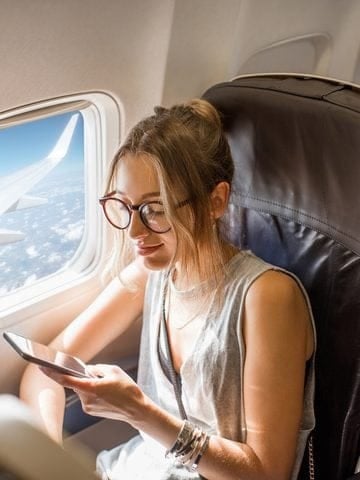 Traveler using a tablet beside an airplane window