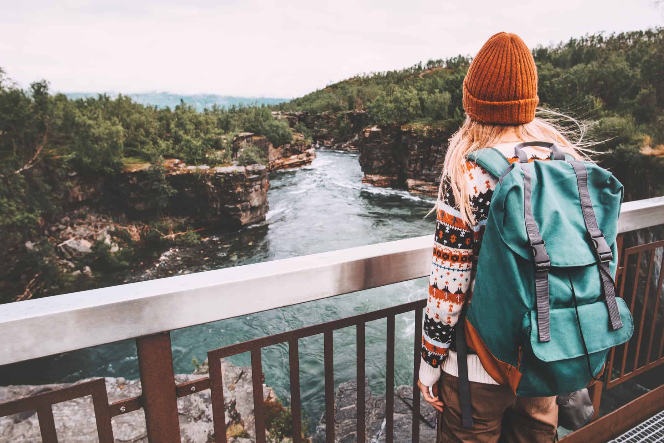 Woman with a backpack overlooking a river canyon in Sweden during a weekend getaway.