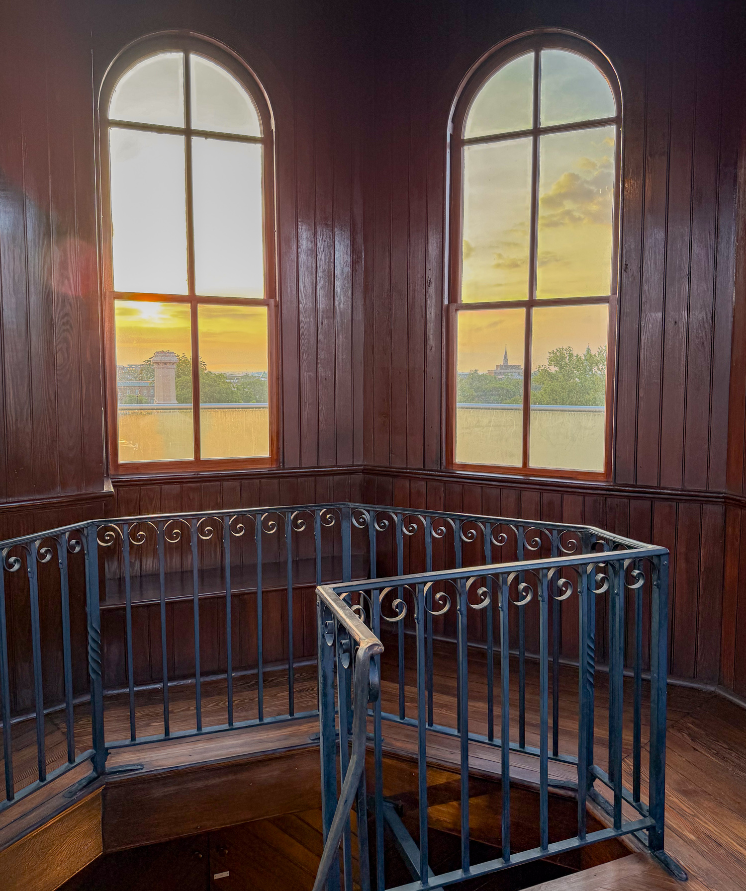Sunrise over Charleston through arched cupola windows above a spiral staircase at Wentworth Mansion.