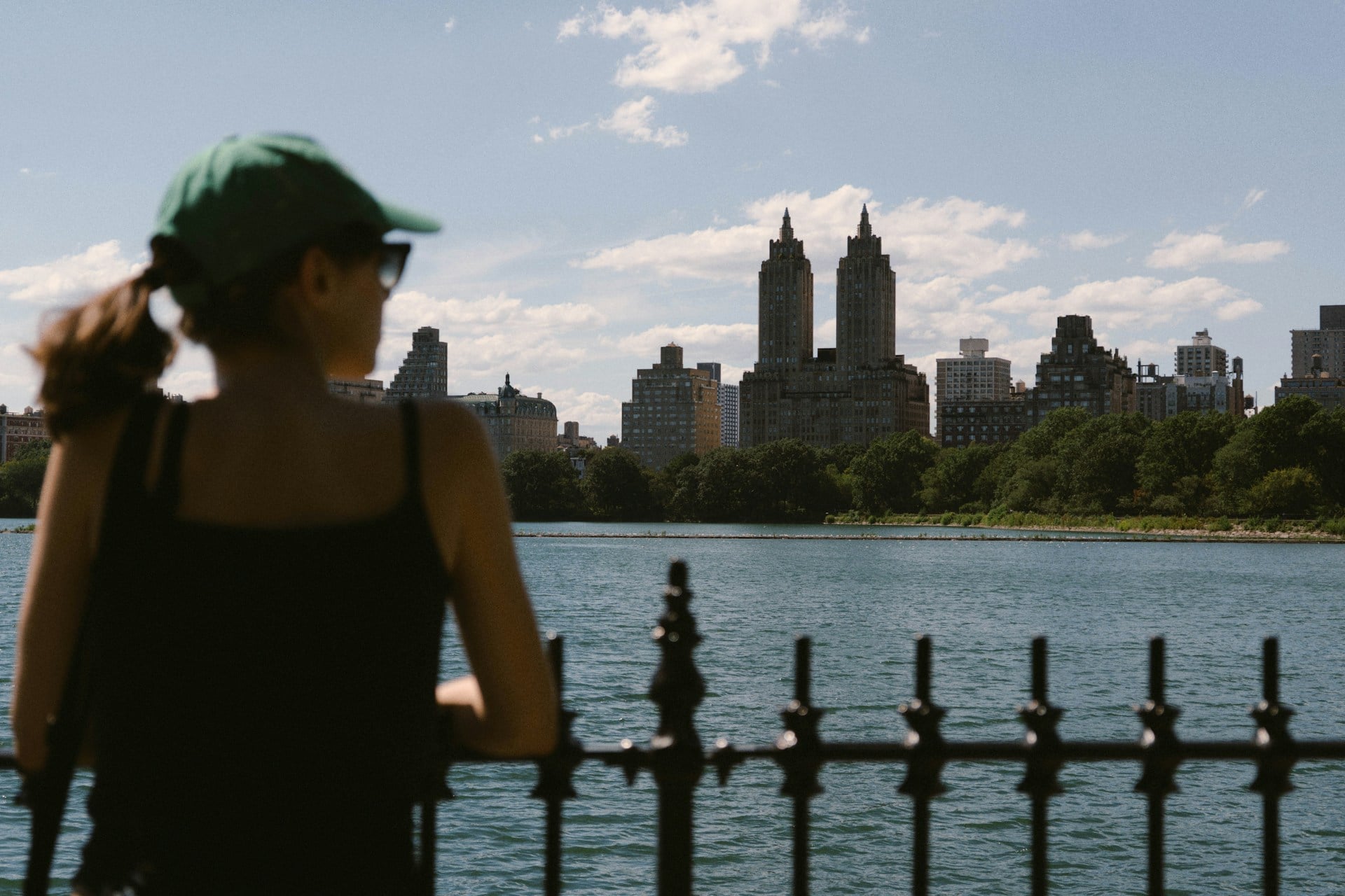 Woman looking across a Central Park lake toward the New York City skyline