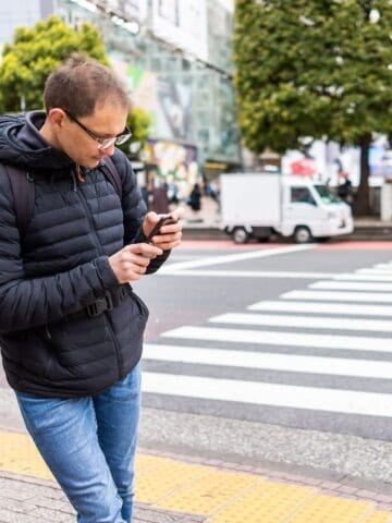 Traveler using a smartphone to navigate Shibuya in Tokyo