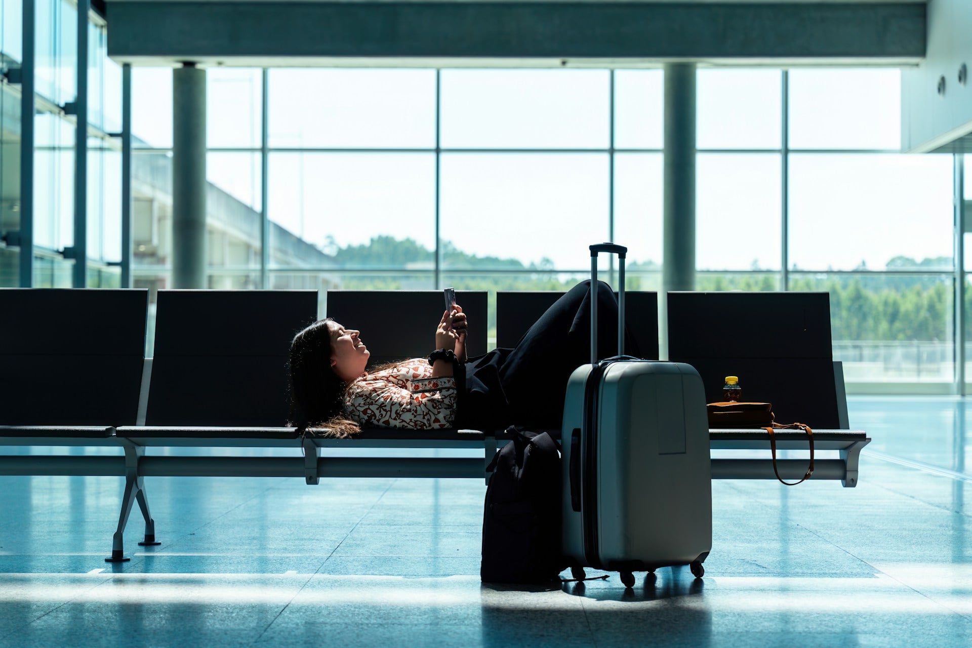 Traveler using a smartphone beside her luggage at an airport