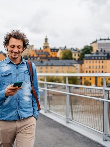 Traveler looking at his smartphone on a bridge in Stockholm, Sweden.